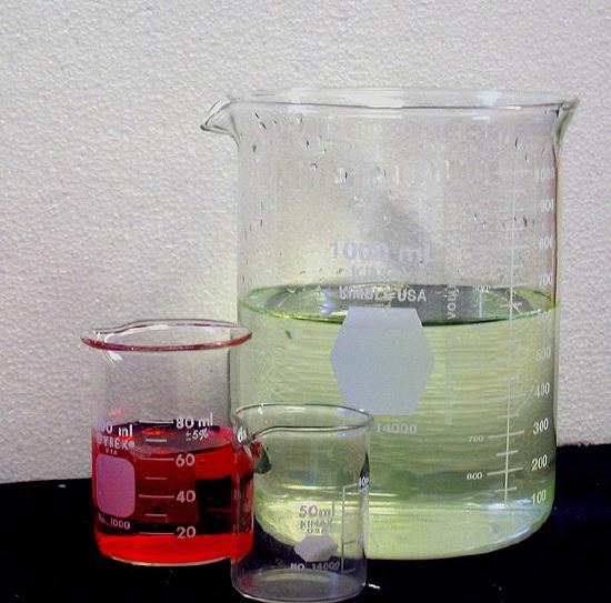 3 different sized beakers with different colored liquids in two, and one is empty.