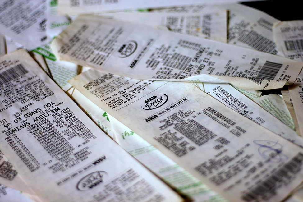 This is a photo of a pile of grocery store receipts. The items and prices are blurred.